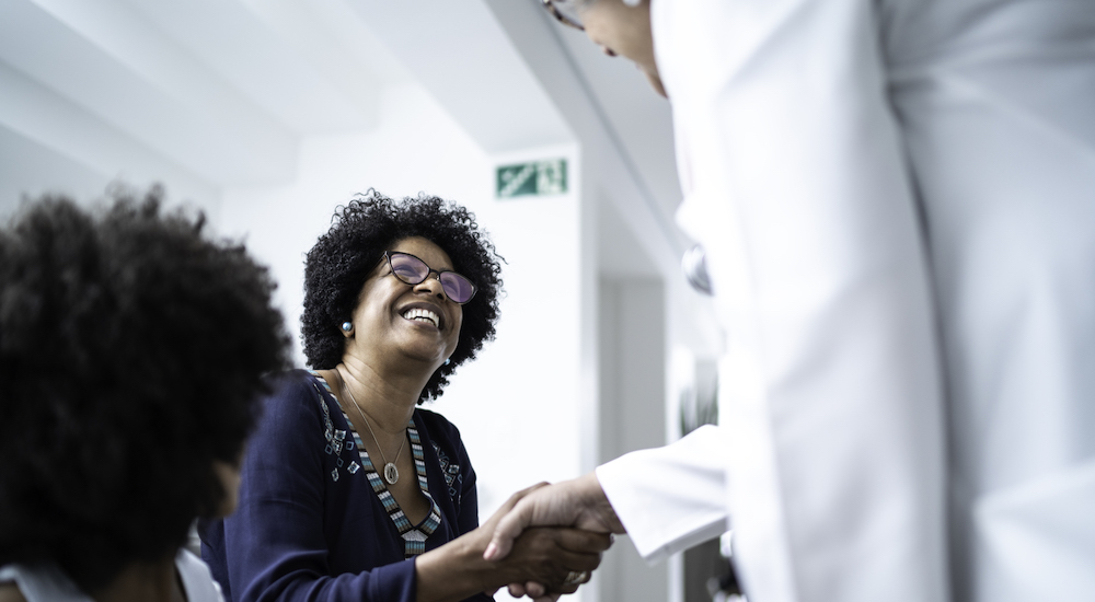 Female senior doctor welcoming / greeting mother and daughter at hospital